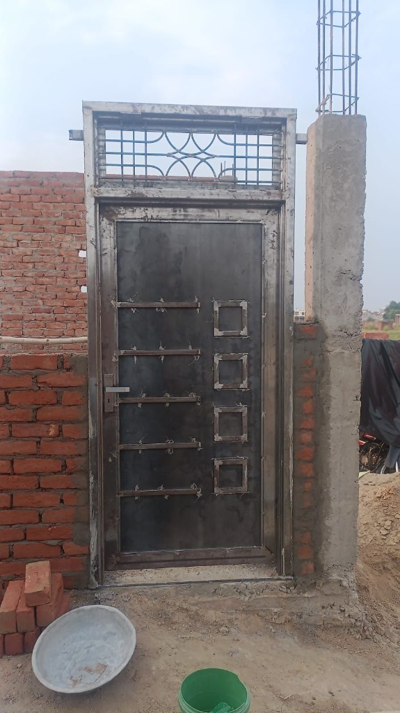 Newly fabricated modern steel safety door frame installed in brickwork by Shiv Construction